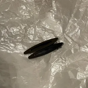Gros plan de barrettes à cheveux noires en métal brillant avec design goutte d'eau ajouré