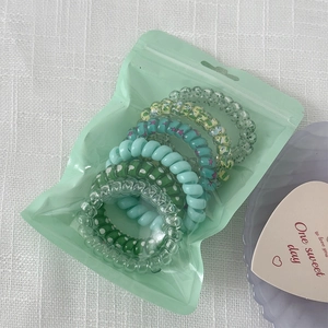 Close-up of colorful spiral phone cord hair ties set in a translucent zipper pouch