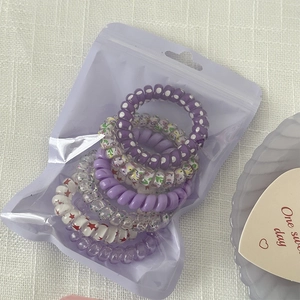 Close-up of pastel purple spiral hair ties set in a frosted translucent zipper storage bag