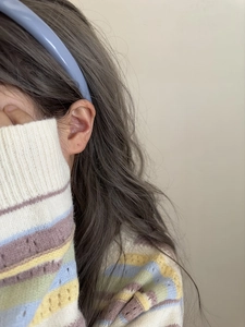 Detail of light blue minimalist headband worn by model in colorful knit sweater