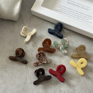 Mini pinces à cheveux en acétate en 10 couleurs variées sur fond gris épuré