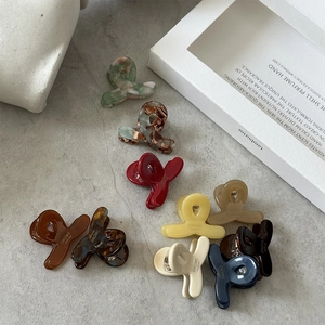 Vue détaillée de mini pinces à cheveux en acétate coloré avec gravure de marque élégante