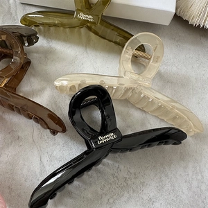 Flat lay of large hair claw clips in black, green, cream, and tortoiseshell colors