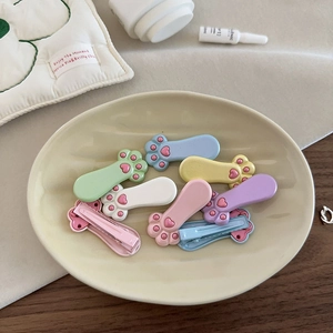 Mollette per capelli a zampa di gatto color macaron in un piatto di ceramica crema