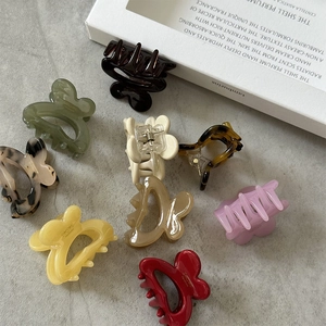 Close-up of colorful acetic acid flower hair clips with smooth glossy finish on grey background