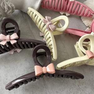 Matte resin bow hair claws in coffee, beige and pink shown on stone background