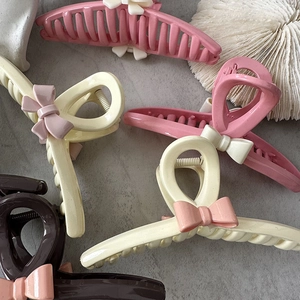 Detailed view of resin bow claw clips in pink, cream and brown on a stone surface