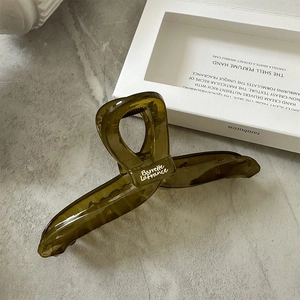 Close-up of translucent olive green hair claw clip with white cursive text detail