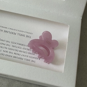 Macro view of light purple butterfly resin hair claw clip with granular texture on magazine