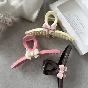 Set of three resin bow hair claws in yellow, pink and brown on a stone surface