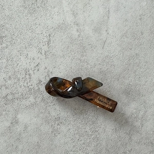 Détail d'une pince à cheveux motif écaille avec logo doré France Handmade gravé