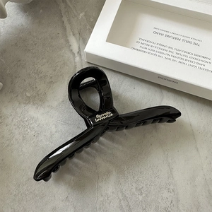 Close-up of black glossy hair claw clip featuring golden Barrette LaFrance elegant lettering