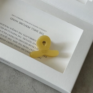 Gros plan détaillé de la mini pince à cheveux en acétate jaune avec logo Sanshine