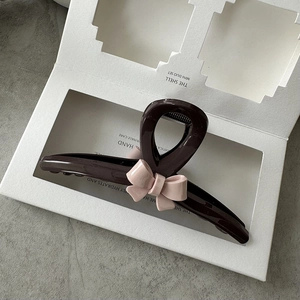 Detailed view of large dark brown resin hair claw clip with a pink 3D ribbon bow ornament