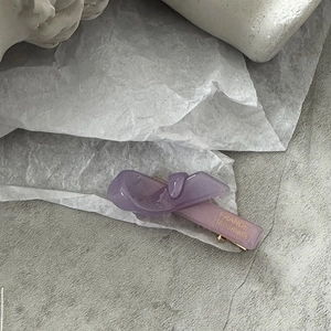 Détail d'une pince à cheveux nœud en résine violette avec lettrage doré fait main