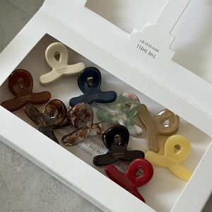 Gros plan de dix mini pinces à cheveux colorées en acétate dans un coffret cadeau blanc