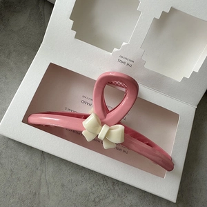 Detail of pink resin hair claw clip with creamy white bow on a display card