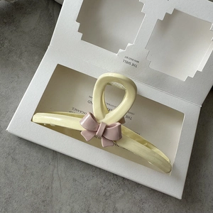Close-up of cream resin hair claw clip with pink 3D bow and non-slip teeth detail