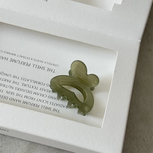 Close-up of a translucent moss green resin mini hair claw clip in a bow-shaped design
