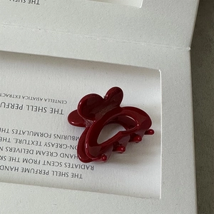 Detail view of a burgundy butterfly hair claw made of high-gloss resin on a white box