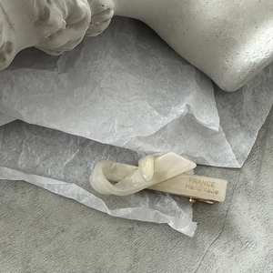Détail de la pince à cheveux blanc crème, texture marbrée, base dorée et gravure à la main