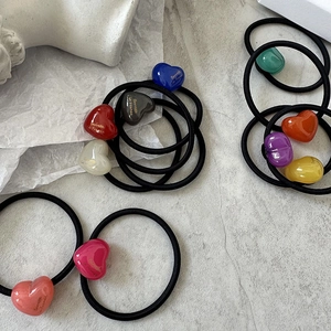 Detailed macro of colorful heart-shaped resin hair ties with gold lettering on elastic bands