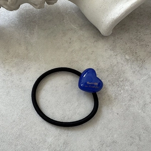 Detailed shot of black elastic hair tie with a glossy bright blue resin heart charm