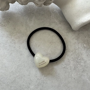 Close-up of minimalist cream heart hair tie with Barrette La France text detail