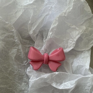 Vue détaillée d'une pince à cheveux rose à double nœud avec une finition brillante