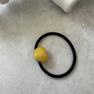 Close-up of black elastic hair tie with a yellow heart pendant and French text