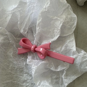Vue détaillée d'une pince à cheveux rose avec finition nacrée et pailletée brillante