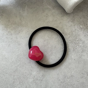 Detail of black elastic hair tie with a shiny pink heart pendant and French lettering