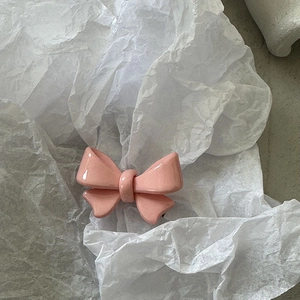 Détail d'une barrette à cheveux nœud rose avec finition acrylique brillante sur papier