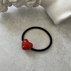 Macro shot of red heart acrylic hair tie with gold Barrette La France text and black band