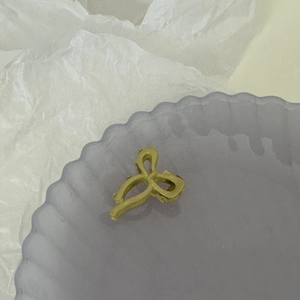 Gros plan d'une pince à cheveux dorée mate en forme de nœud sur un plateau lavande