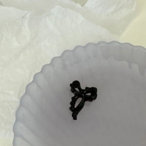 Vue détaillée de la mini pince à cheveux noire en forme de ruban en résine polie