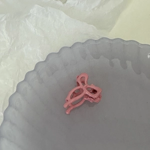 Gros plan d'une petite pince à cheveux rose mate en ruban sur un plateau en verre