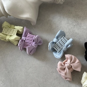 Pinces à cheveux avec nœuds en satin de couleurs variées sur fond esthétique