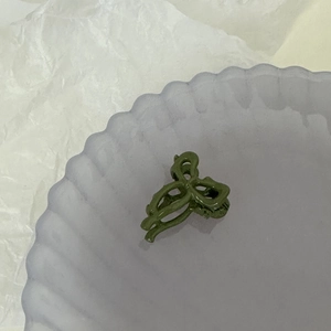 Vue détaillée d'une mini pince à cheveux vert foncé en forme de nœud sur un plateau