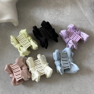 Vue détaillée de 6 pinces à cheveux à nœuds en satin colorés sur un fond en pierre