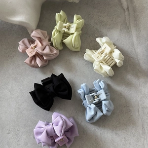 Pince à cheveux nœud en satin en six coloris doux sur fond de marbre élégant