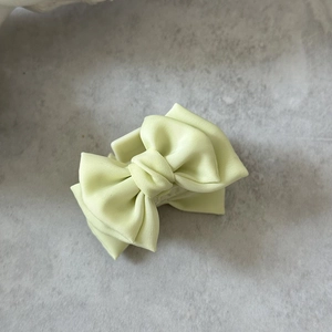 Détail d'une pince à cheveux à nœud en satin vert clair avec une texture de soie raffinée