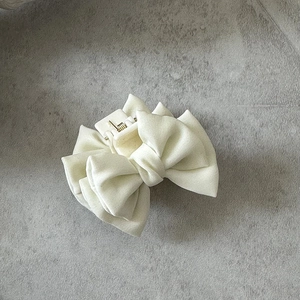 Vue détaillée de la petite pince à cheveux à nœud en satin crème au fini mat
