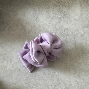 Détail d'une pince à cheveux avec nœud en satin violet et texture de tissu multicouche