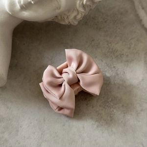 Gros plan sur la pince à cheveux en satin rose montrant la texture plissée