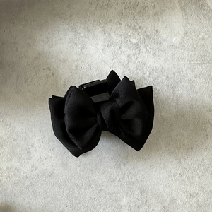 Détail d'une pince à cheveux élégante en satin noir avec ruban multicouche texturé