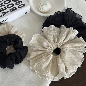 Vue détaillée des chouchous plissés surdimensionnés en noir et beige au tissu en mousseline