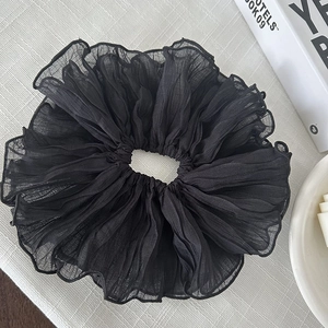 Détail d'un grand chouchou noir plissé en mousseline avec une texture élégante
