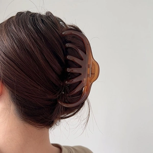Macro shot of large amber daisy hair claw clip securing thick hair on model