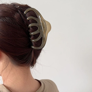 Translucent olive green resin hair claw clip shown styling thick hair in a back view